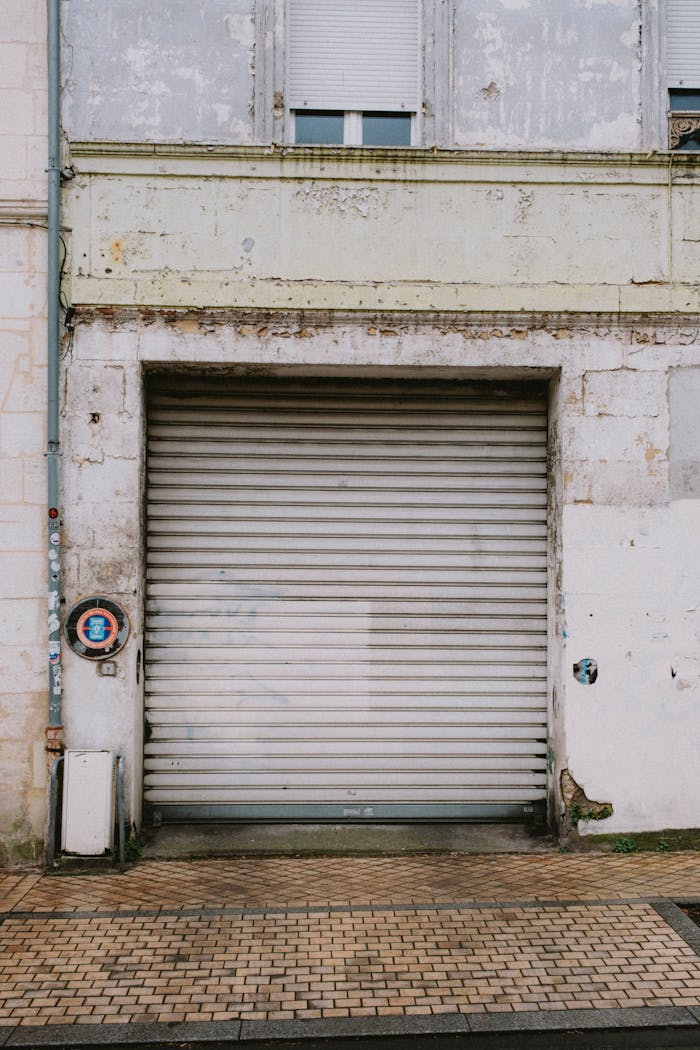 services-03 An old garage door with a weathered wall, showcasing urban decay and texture.