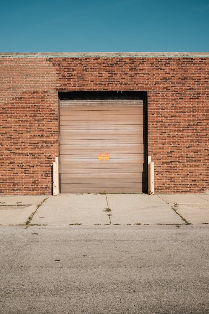 services-04 A brick warehouse with a closed roller door under a clear blue sky.