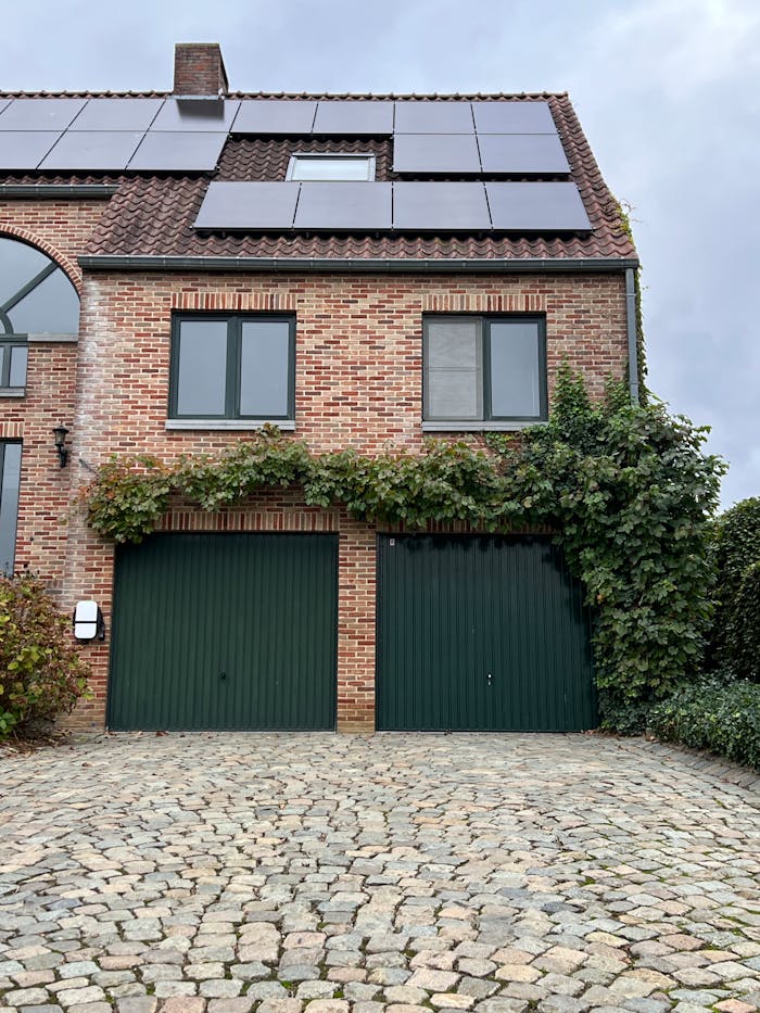 services-01 Charming brick house with solar panels and ivy-covered garage. Eco-friendly architecture.
